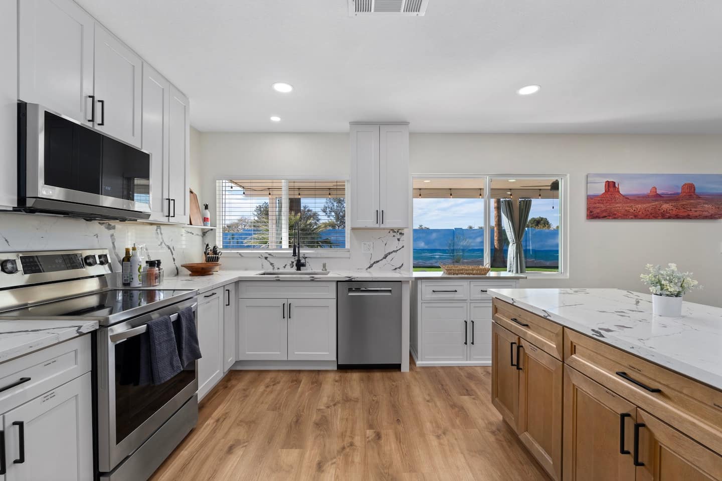 Full kitchen at South Mountain Lagoon with white shaker cabinets, marble-look counters, stainless appliances and a window onto the backyard mural