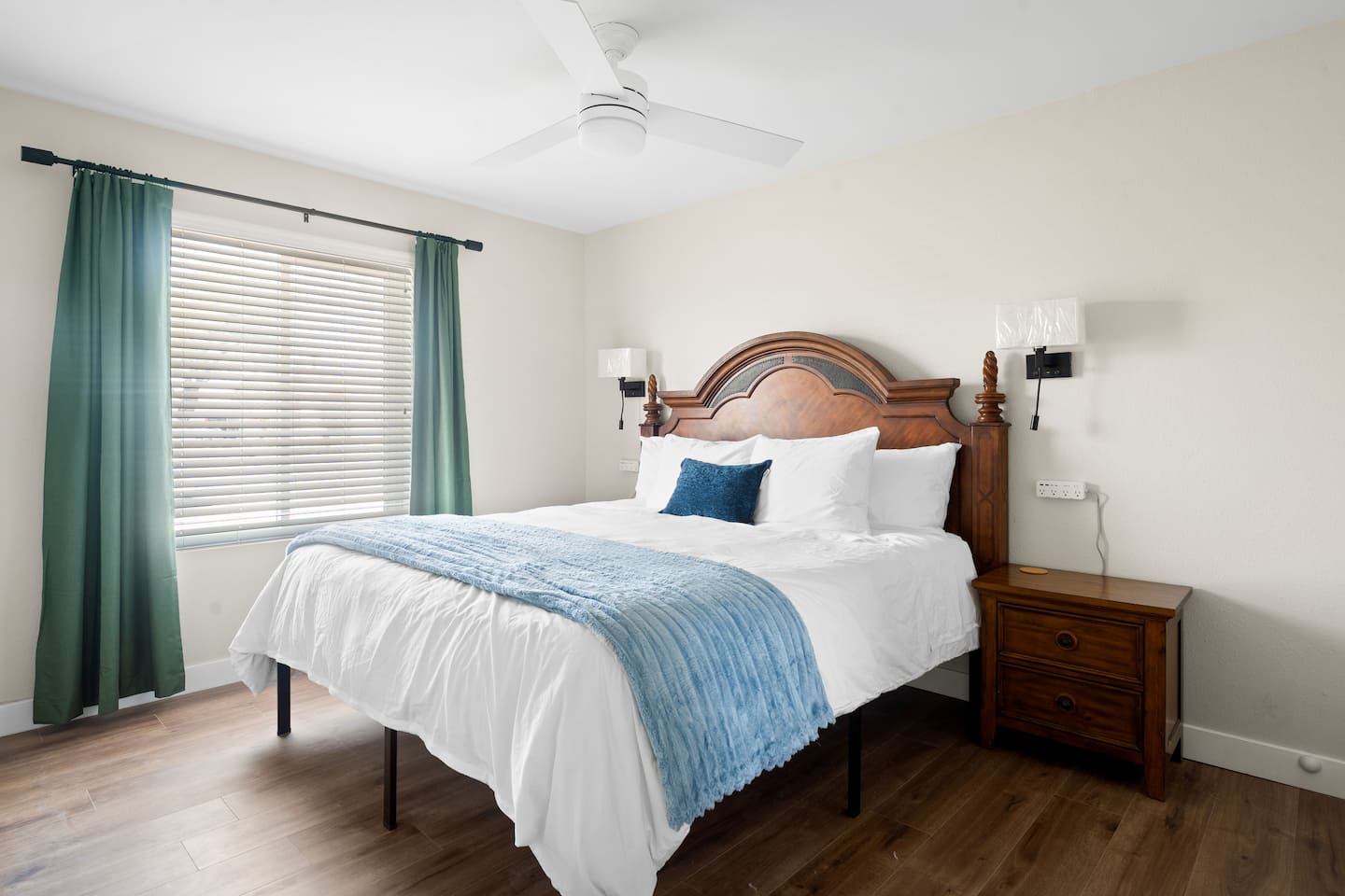 Second king bedroom at South Mountain Vista, with a blue throw, green curtains and a wooden nightstand