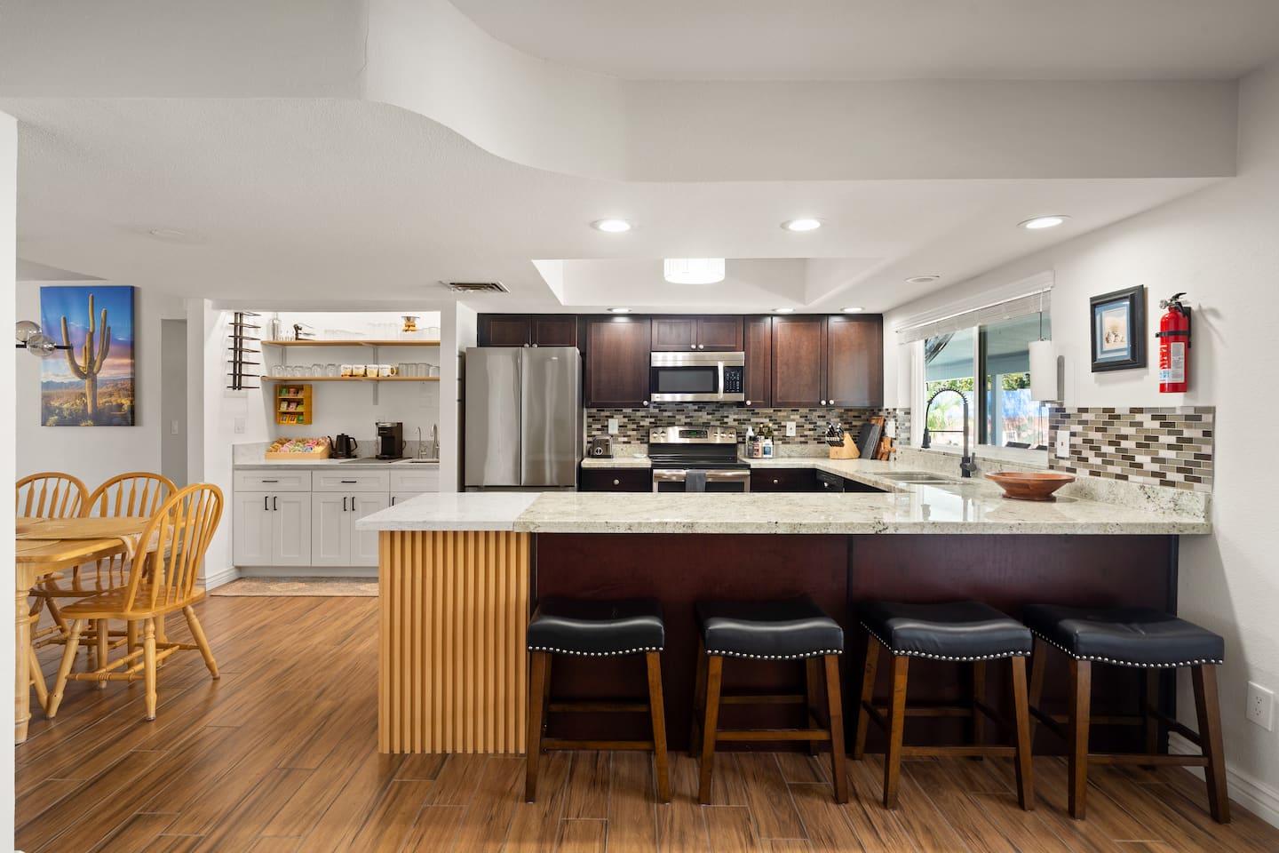 Kitchen at South Mountain Vista with a long granite breakfast bar, four leather stools, dark cabinetry and the coffee bar in the corner