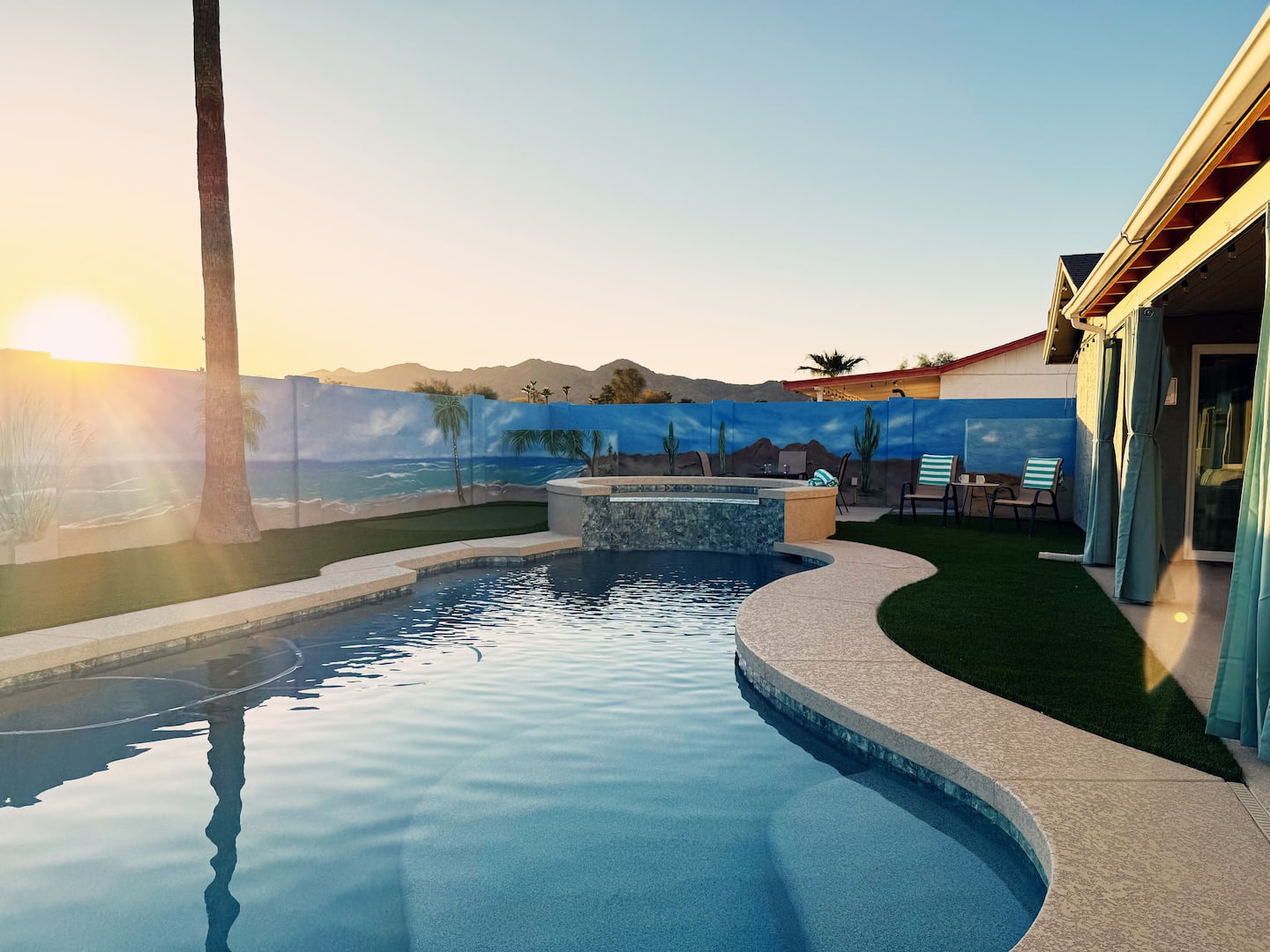 The pool and raised spa at South Mountain Lagoon with the sun low over the mountain ridge behind the mural wall