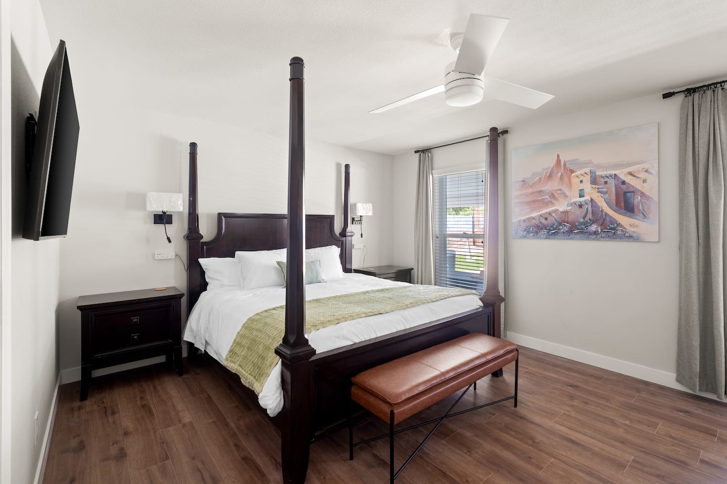Primary suite at South Mountain Vista: a dark four-poster king bed with a leather bench, a wall-mounted TV and desert artwork