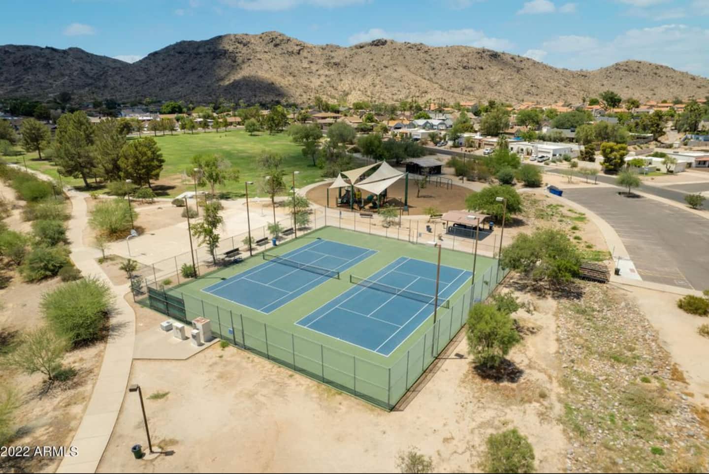 Aerial view of Western Star Park, with tennis courts, a shaded playground and green fields at the foot of South Mountain